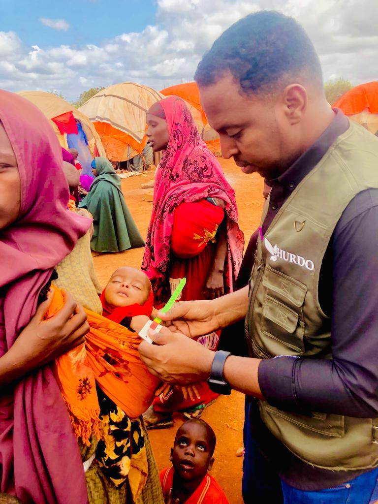 HURDO staff measuring a child's mid-upper arm circumference at a displacement site