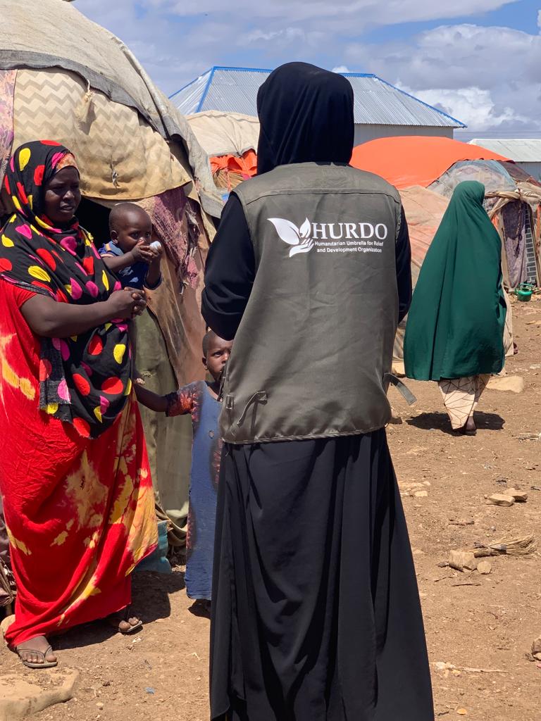 HURDO staff speaking with a woman and child at a displacement site