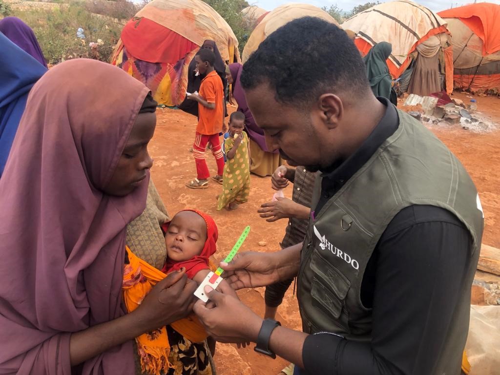 HURDO staff measuring a child's mid-upper arm circumference during a community nutrition visit