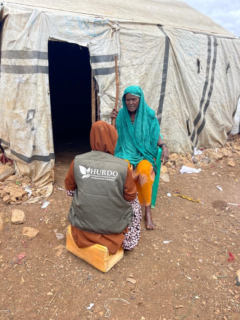 HURDO staff speaking with a woman outside a tent